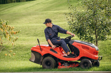 Sitting on the lawn mover. Professional gardener is on the lawn