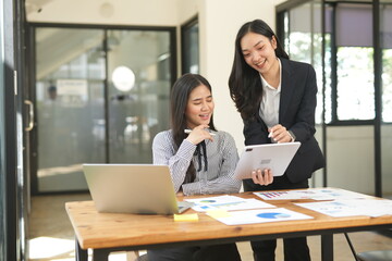 Group of happy Asian business people having a meeting at the office. Two women working together using modern laptops.