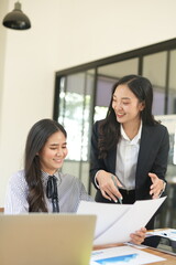 Happy Asian business people working together using laptop and tablet in office.