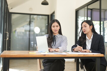 Two businesswomen are considering documents in an office.