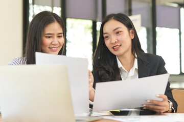 Group of happy Asian business people having a meeting at the office. Two women working together using modern laptops.