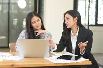  Group of happy Asian business people having a meeting at the office. Two women working together using modern laptops.