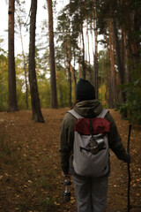 tourism. a tourist with a gray-burgundy backpack, mugs, a lantern with a compass travels through the wild forest