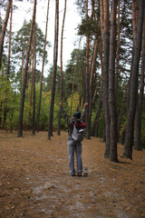 Fototapeta premium tourism. a tourist with a gray-burgundy backpack, mugs, a lantern with a compass travels through the wild forest