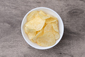 Potato chips in a bowl over wooden table