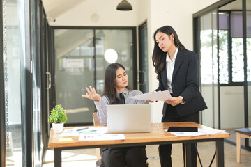 Two businesswomen are considering documents in an office.