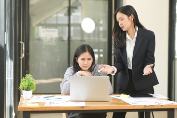 Happy Asian business people working together using laptop and tablet in office.