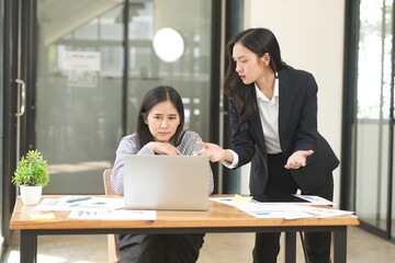 Happy Asian business people working together using laptop and tablet in office.