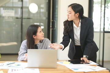 Happy Asian business people working together using laptop and tablet in office.