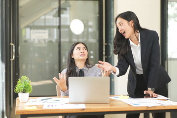 Happy Asian business people working together using laptop and tablet in office.