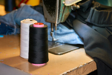 A spool of black white threads on an old sewing machine in a tailor's workshop
