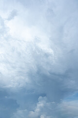 Fluffy white clouds drift across a vibrant blue summer sky