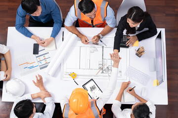 Top view banner of diverse group of civil engineer and client working together on architectural project, reviewing construction plan and building blueprint at meeting table. Prudent
