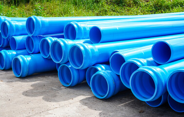 Stack of large blue water pipes, PVC nylon water pipes unpacked used on the construction site for installation, water supply repair or plumbing drain infrastructure earthworks.