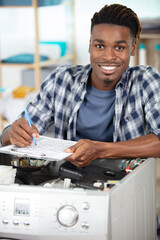 working man repairs washing machine in laundry room