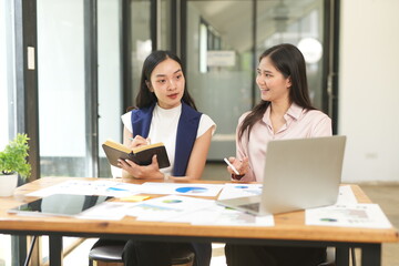 Happy Asian business people working together using laptop and tablet in office.