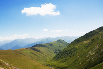 Obraz premium Scenic views on mountain and valley at summer. Green meadows and forests, slopes, hilly countryside, blue sky with clouds. Beautiful landscape, travel background, wallpapers and banner.
