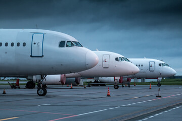 The noses of white passenger planes at the airport on an early cloudy morning