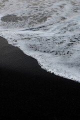 Close-up view of some waves crashing on a black sand beach. Natural background, wallpaper. Iceland.