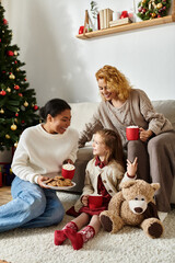 The cheerful couple shares cookies and cocoa with their daughter by the festive tree