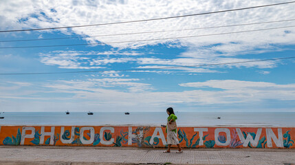 A Girl walks in front of a mural with the word Phuoc Hai Town at in Dat Do District, Bà Rịa–Vũng Tàu province, Vietnam. © Lam Charles