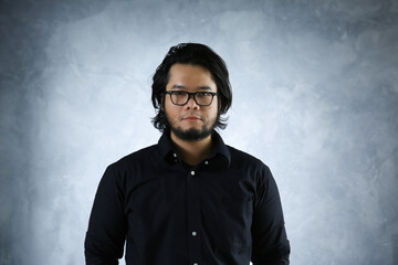 portrait of an Asian man in black shirt wearing eye glasses on abstract background