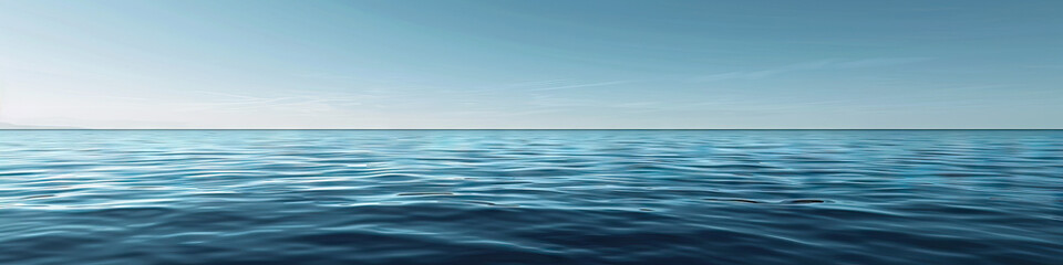 Fototapeta premium A calm blue sea, its surface dotted with small whitecaps under a clear sky.