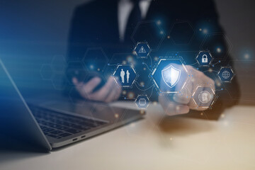 A man is using a laptop with a blue shield icon on the screen