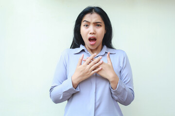 shocked asian young woman wearing formal office clothes stunned looking at camera with open mouth and hands on chest, standing over isolated white background