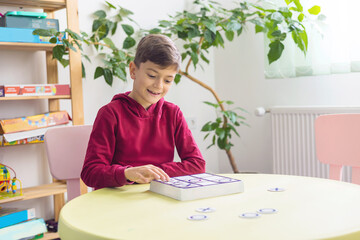 a little boy in the children's room plays tic-tac-toe. The topic of early development, speech development, child development, intellectual and logical skills. Themes of inclusive coverage, education.