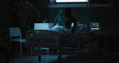 African woman is lying on a bed in a ward suffering from severe abdominal pain.