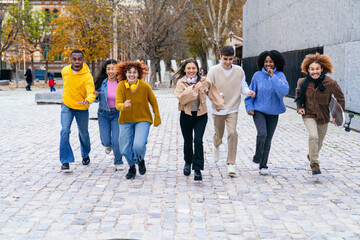 Fototapeta premium Multiethnic group of young people running down the street