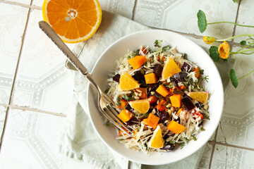 bowl of salad with beetroot, pumpkin, orange and nuts on light table