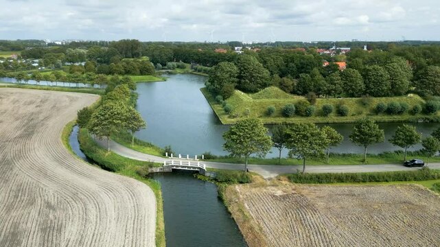 car crossing bridge over small road water fortifications visible around structure scenic architectural forward aerial shot view motion architecture dutch engineering 