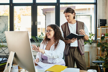 A young plus size woman engages joyfully with her male friend while working on a project together.