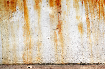 Rust on white paint cement wall. The pattern of grunged rust on wall use as illustration for presentation background.Rusty corrosion and oxidized background.