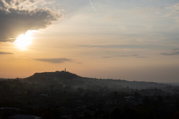 La silhouette del borgo di Formeniga, in provincia di Treviso, Veneto, Italia, contro il cielo arancione all'alba di un giorno d'autunno, lungo il cammino delle colline del Prosecco