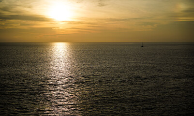 Breathtaking sunset scene, tourist boat in beautiful seascape and sky reflecting on the tranquil waters, creating a serene and picturesque setting.High view form Promthep Cape, Phuket, Thailand.