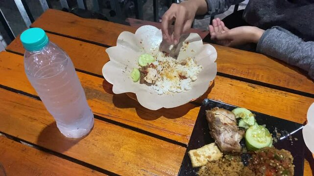 Eating "Ayam Geprek" Indonesian Traditional Food with chili Suce at the restaurant