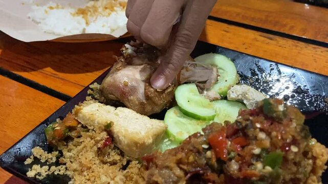 Eating "Ayam Geprek" Indonesian Traditional Food with chili Suce at the restaurant