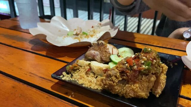 Eating "Ayam Geprek" Indonesian Traditional Food with chili Suce at the restaurant