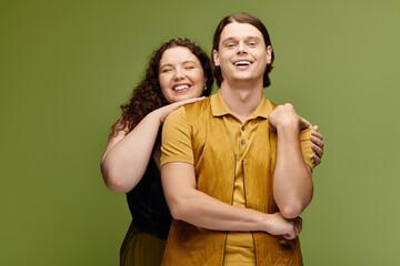 Two friends happily pose together in a studio with a bright green backdrop.