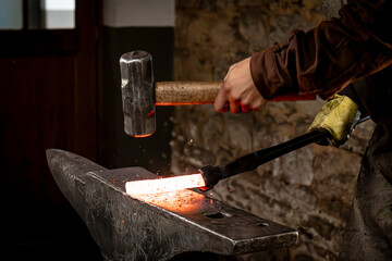 Craftsman - blacksmith manually forging the molten metal with a hammer