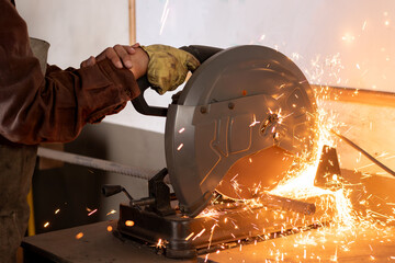 craftsman or industrial worker using a miter saw to cut metal