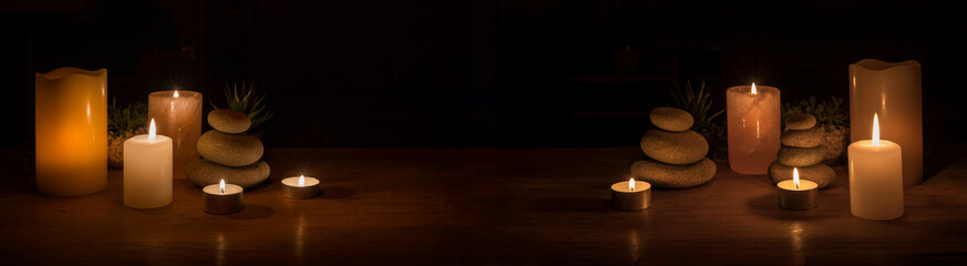 image in panorama mode with decorative objects such as candles, stones and plants in a dark environment