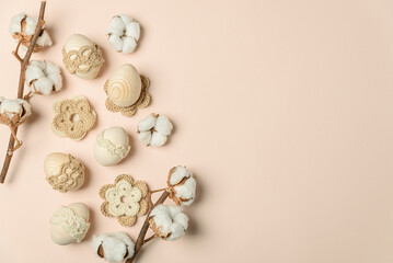 Craft eggs, knitted and cotton flowers on soft beige background. Top view. Copy space