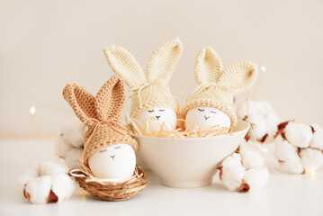 Easter eggs in crochet knitted hats with rabbit ears in nest. Easter celebration concept