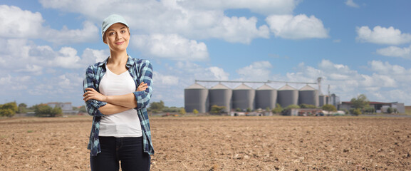 Female farmer posing with crossed arms on a field with silos © Ljupco Smokovski