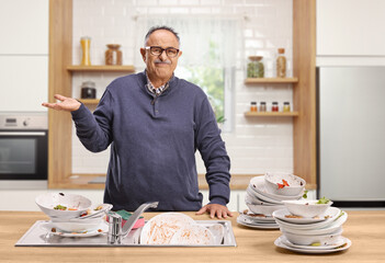 Angry mature man with a pile of dirty dishes