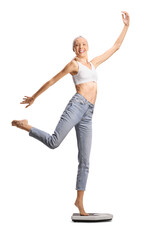 Tall slim woman in jeans and white crop top dancing on a weight scale